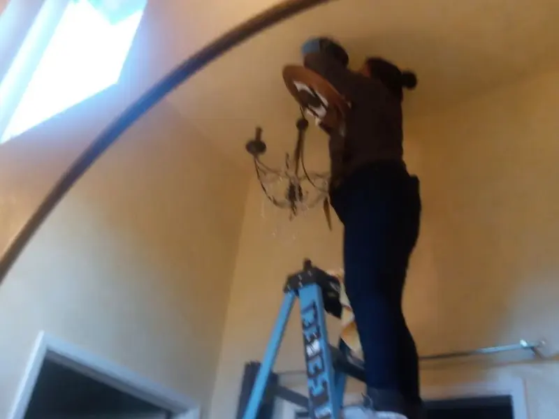 Electrician installing a chandelier in a Itasca residence